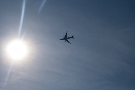 An airplane from below with lots of sky and bright sun