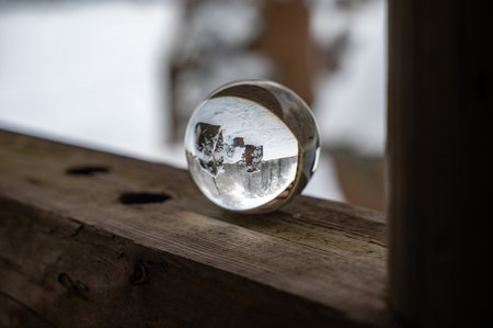 Glass ball on a wood on a cold winter day, with reflections of trees and snow in the glassの写真素材