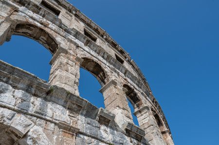 Part of the Pula Arena, the sixth largest amphitheater of its kind, with a blue sky in Croatia,...