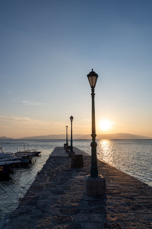 Lanterns on a pier with boats, by the sea at sunsetの写真素材