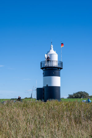 The Little Prussian lighthouse, with people and a blue sky, is open to visitors in the town of...
