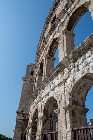 Part of the Pula Arena, the sixth largest amphitheater of its kind, with a blue sky in Croatia,...