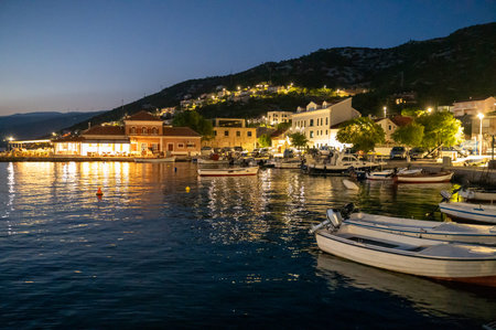 View of the illuminated harbor with some boats in the small fishing village of Sveti Juraj on the...