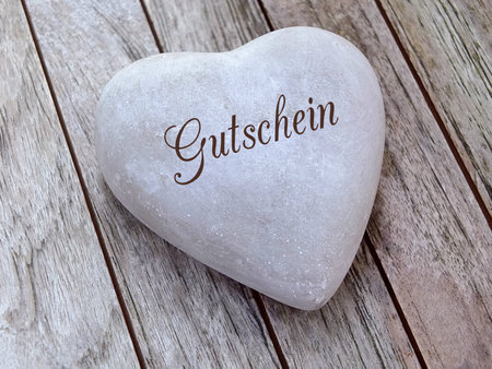 Stone heart on a wooden background with german textの写真素材