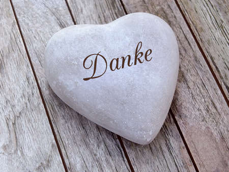 Stone heart on a wooden background with german textの写真素材