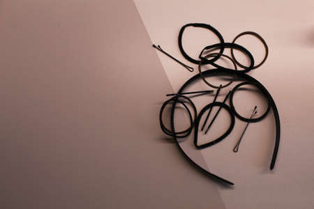 A hairband, some hair ties and some bobby pins on a white and light brown backgroundの写真素材