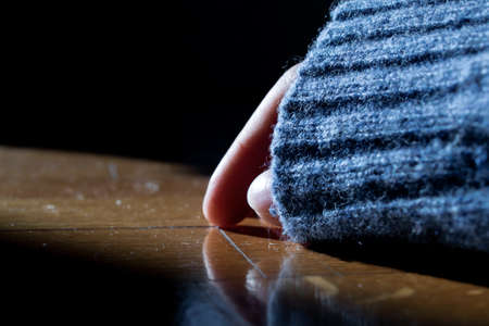Hand partially covered with a blue sleeve lying on a parquet floor