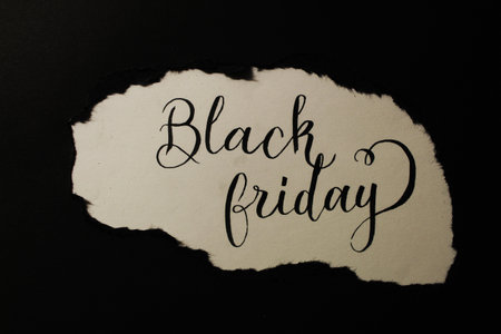 Ripped black piece of paper uncovers a writing saying "Black Friday"の写真素材
