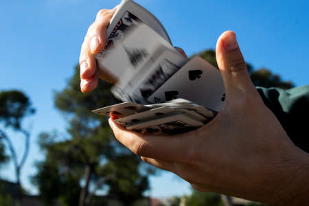 Unrecognizable boy shuffling a deck of cards. Blurred cards in motion. Selective focus.の写真素材