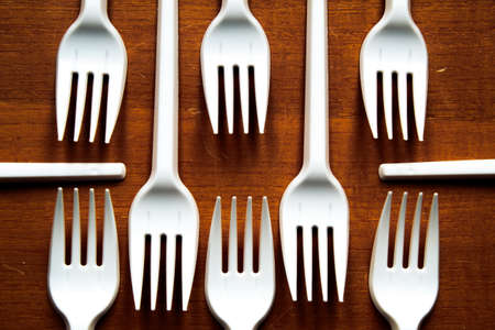 Some plastic forks placed in a geometric pattern, on a wooden table.の写真素材