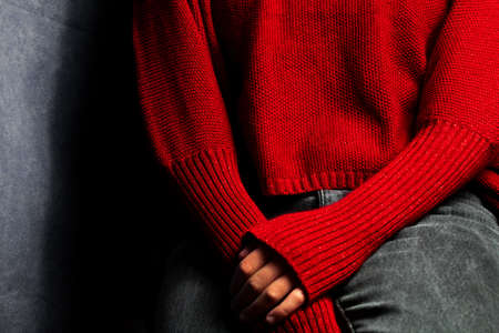 Close up of woman's hands in red knitted sweater on black backgroundの写真素材