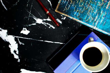 Cup of coffee, book and pen on black marble table.の写真素材