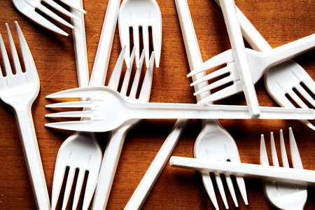 Disposable plastic tableware on a wooden background. Disposable tablewareの写真素材