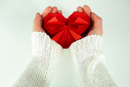 A girl is holding with her hands a paper heartの写真素材
