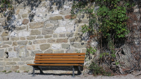 Wooden bench in front of stone wallの写真素材