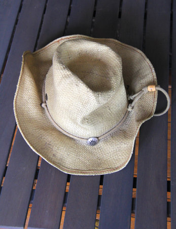 Straw sun cowboy hat on wooden table, closeup of photo with soft focus.の写真素材