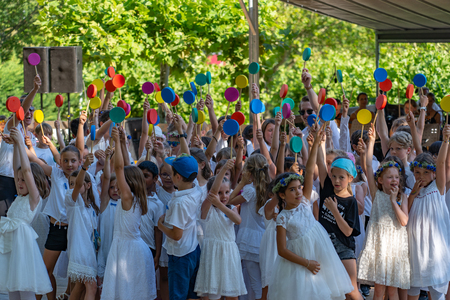 Elementary students ending a dance by extending arms in height holding multicolored lillipops in their hands on the 4th of july at Jugendfest Brugg 2019.のeditorial素材
