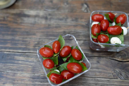 Closeup of red cherry tomatoes with fresh basil and mozzarella cheese. Appetizers sprinkled with...