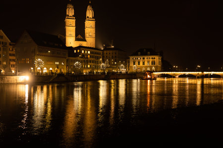 Major church GrossmÃ¼nster in old town of zurich days before Christmas. View over bridge to a fire place on a raft on the river Limmat. Zurich, December 19, 2020.の写真素材