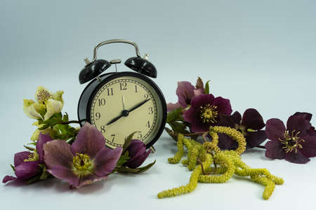 Vintage clock with spring flowers. Daylight saving time concept.