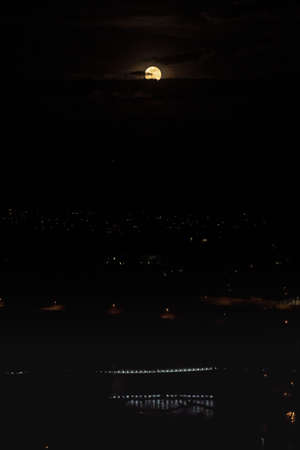 Super moon in deep dark night in Switzerland with blue illuminated Muellimatt Bridge over Aare in...