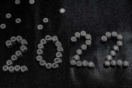 High angle view of New Years 2022 as Swiss coins on a black shiny ground with silver star. Concept for money, new year, coins.の写真素材