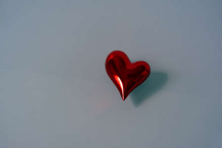 Isolated red shiny heart on blue glass background. Copy space for text.の写真素材