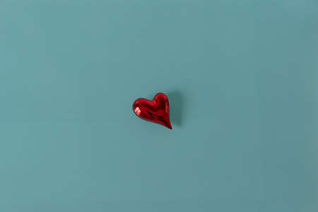 Isolated red shiny heart on turquoise glass background. Copy space for text.の写真素材