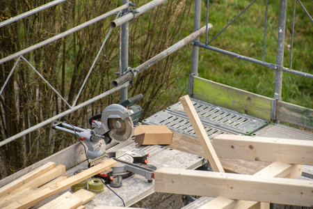 Circular saw from carpenter on a railing next to rafter of a new wooden roof.