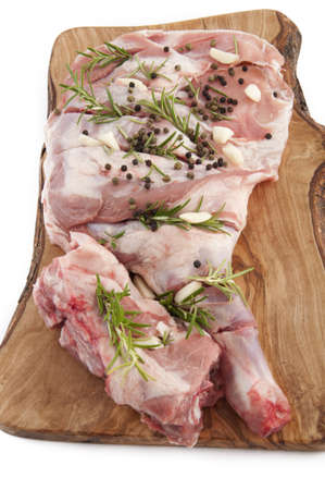 leg of lamb seasoned with rosemary and raw garlic on a white backgroundの写真素材