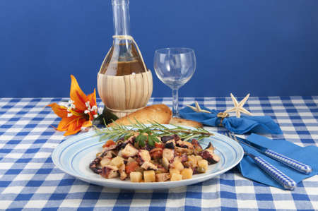 octopus with potatoes and olives to the piata with a bottle of wineの写真素材