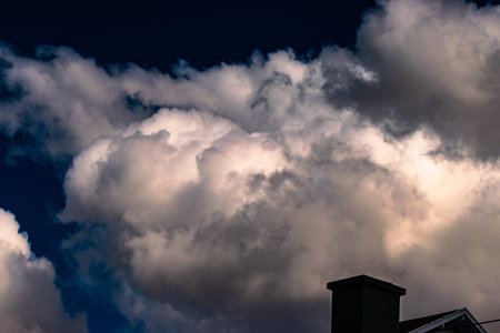 view of stunning cumulus cloud formation after storm illuminated by sun in blue autumn sky at...