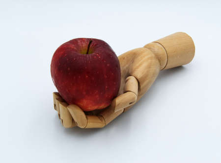 Wooden hand holding red apple.の写真素材
