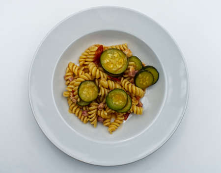 Fusilli pasta with zucchini and speck isolated on white background. Top viewの写真素材