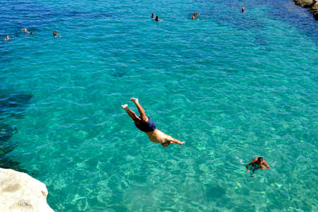 Valletta / Malta - September 11, 2011: Man is diving into the crystal clear waters of Malta from the...