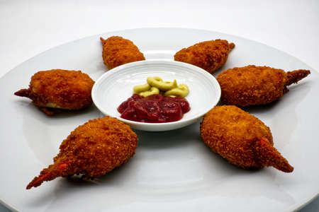 Baked crab claws with ketchup and mustard sauces in a white dish