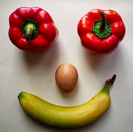 Smiley face made of peppers, egg and banana, isolated on white background.の写真素材