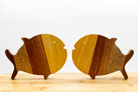 Wooden fish figures on wooden table, white backgroundの写真素材