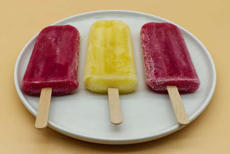 Yellow and purple ice pops ice cream sticks in a white dish