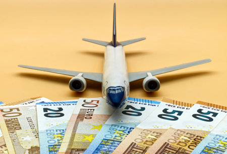 Commercial airplane toy and a pile of Euro banknotes. Flights cost conceptの写真素材