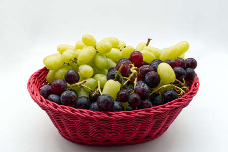Fresh Red and White Grapes in a red basket isolated on white background.の写真素材