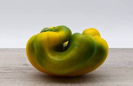 Fresh raw half green and half yellow sweet pepper on wooden table.の写真素材