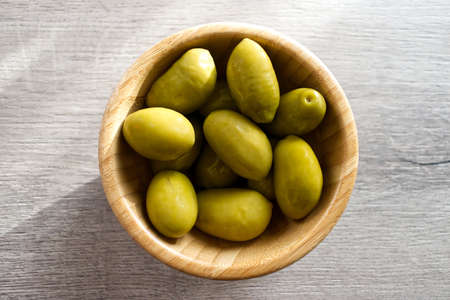 Bowl with Italian green olives from Cerignola. Bella di Cerignola Italian olives on wooden table. Top viewの写真素材