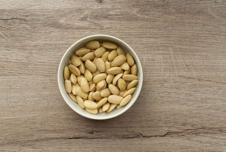 Almonds in a bowl on wooden background. Top viewの写真素材