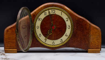 Vintage Italian wooden table clock on marble table and black background.