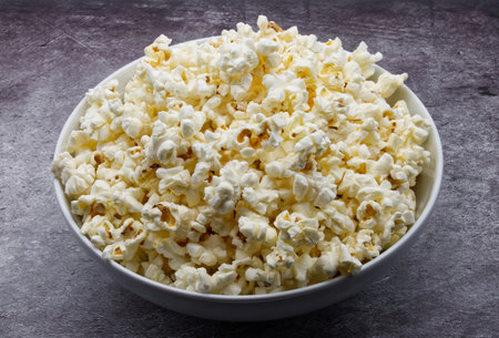 Bowl of fresh popcorn isolated on gray concrete background.