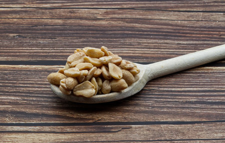Pealed Peanuts in a wooden spoon isolated on wooden background