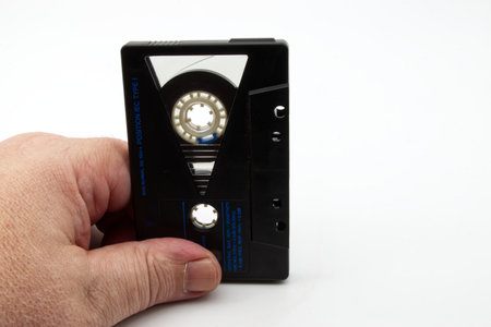 Male hand holding a vintage Audio Cassette Tape isolated on white background. Vintage technology...
