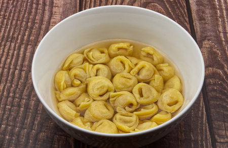 Traditional Italian Tortellini in broth on wooden table.の写真素材