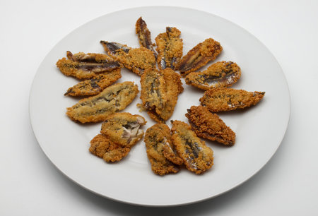 Delicious anchovy fish fry, fried breaded anchovies, on white dish isolated on white background.の写真素材